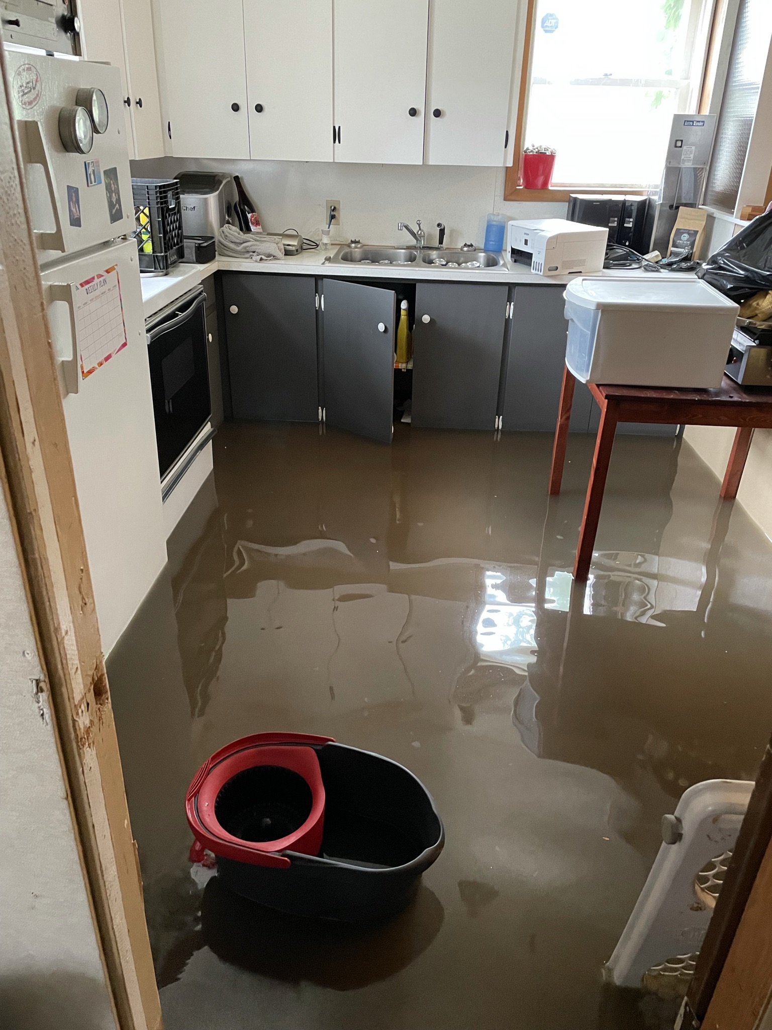 Flooded kitchen with standing water on floor reflecting cabinets, indicating a need for Water Damage Restoration in Canada Wide Restoration.com services